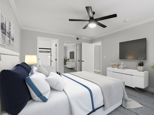 Carpeted bedroom with ceiling fan and private bathroom.