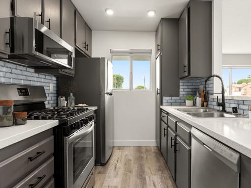 Tiled kitchen with stainless steel microwave, oven, and fridge.