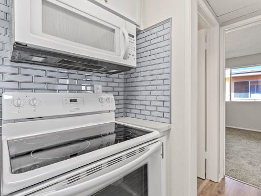 White tiled kitchen with stainless steel oven and microwave.