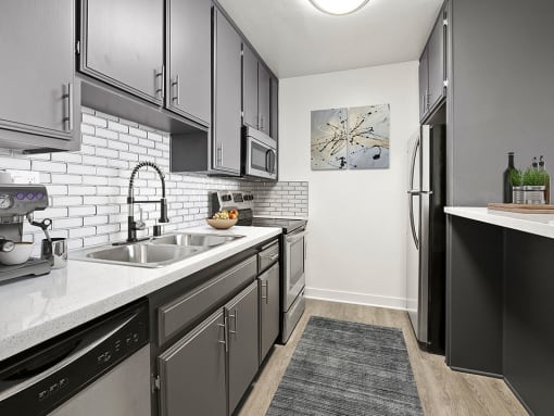 White tiled kitchen with stainless steel fridge, microwave, and oven.