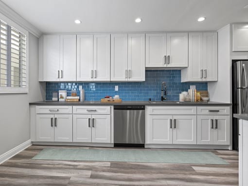 Blue tiled kitchen with stainless steel dishwasher and fixtures.