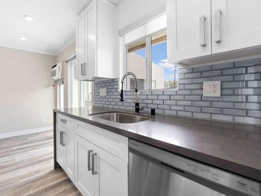 Blue tiled kitchen with stainless steel oven, fridge, dish washer, and fixtures.