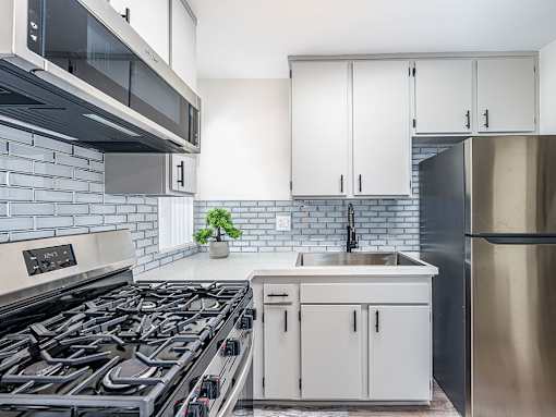 Tiled kitchen with stainless steel fridge, oven, and miocrowave.