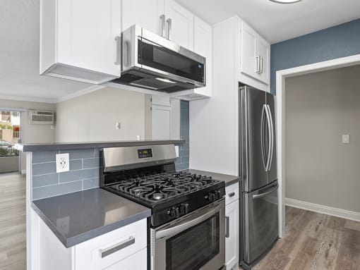 Kitchen with blue tile backsplash and stainless steel Stove, Oven, and fixtures.