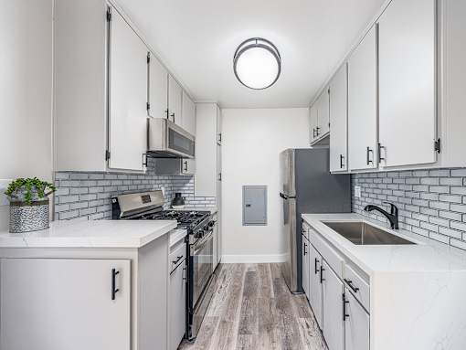 Tiled kitchen with stainless steel fridge, oven, and miocrowave.