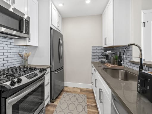Blue tiled kitchen with stainless steel fridge, oven, and fixtures.