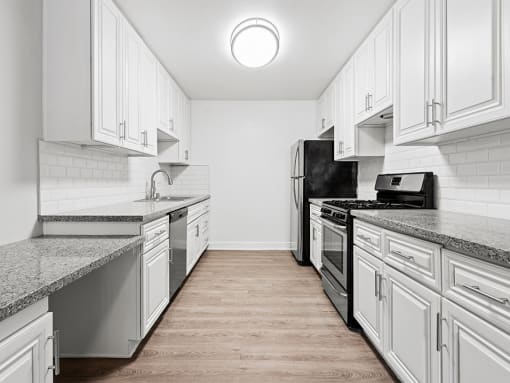 Large white tiled kitchen with stainless steel oven, microwave, and fridge.