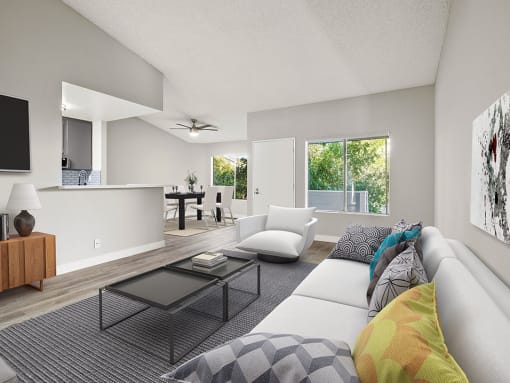 Hardwood floored living room with large windows and view of kitchen.