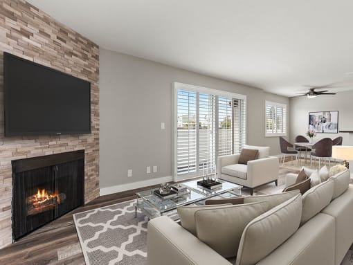 Hardwood floored living room with stone accented fireplace and large exterior windows.