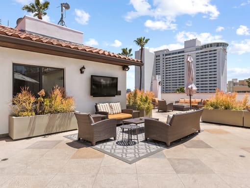 Open air rooftop patio with gas firepit, BBQs, several seating locations, and cable television.