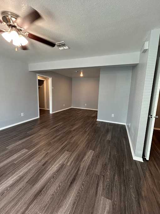 A room with a ceiling fan and wood flooring.