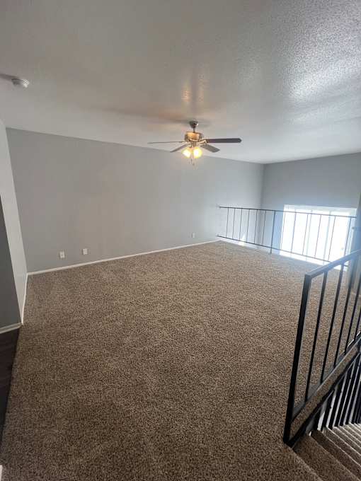 A room with a ceiling fan and carpeted floor.