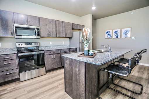 A kitchen with a wooden island and a black chair.
