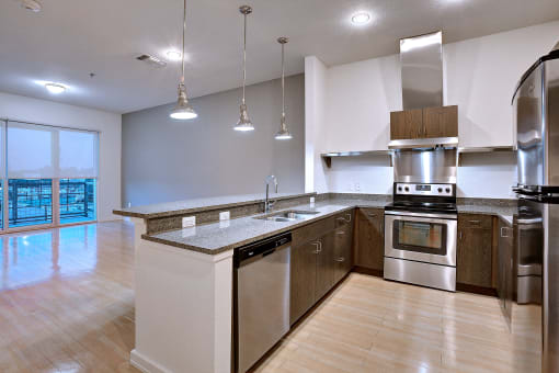 Beautiful apartment kitchen with stainless steel appliances and granite counters and bar at The Mosaic on Broadway, San Antonio, 78215
