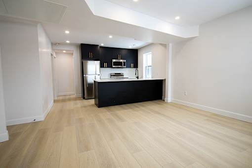 A kitchen with a black countertop and wooden flooring.