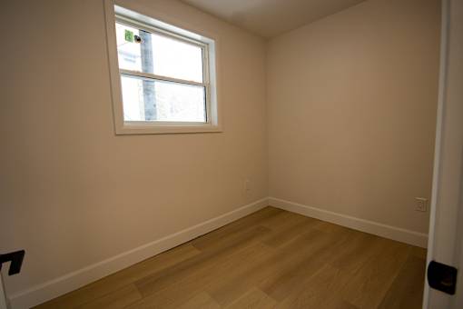 A room with a window and wooden flooring.