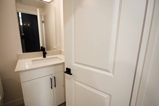 A white bathroom with a sink and mirror.