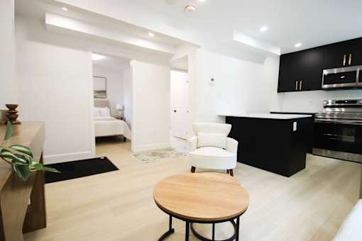 A modern kitchen with a black counter and a white chair.