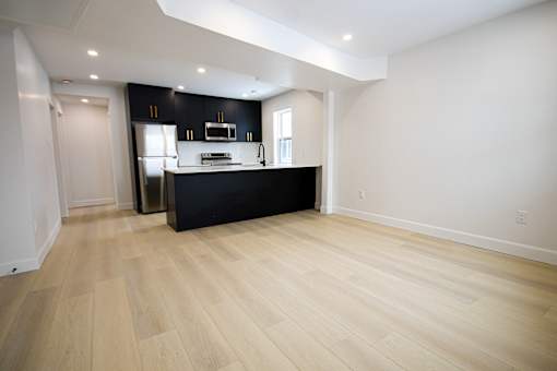 A kitchen with a black counter top and wooden flooring.