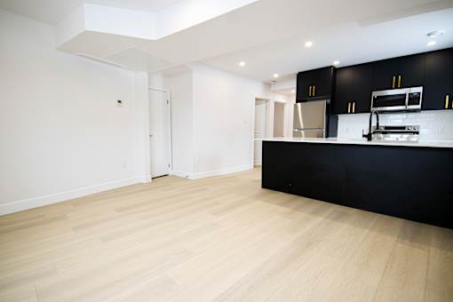 A kitchen with black cabinets and a wooden floor.