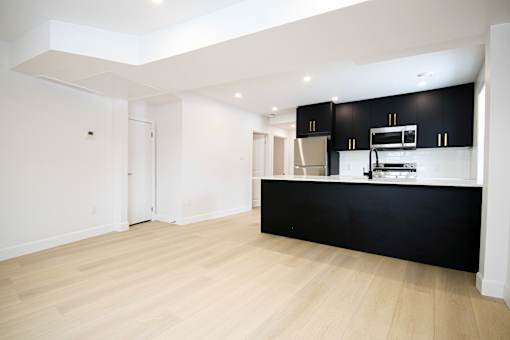 A kitchen with black cabinets and a wooden floor.
