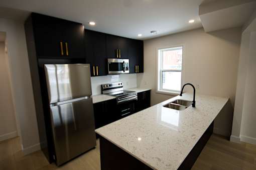 A kitchen with a stainless steel refrigerator and a granite countertop.