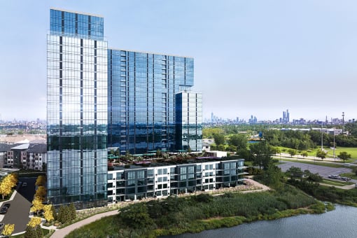 Exterior photo of RVR showing the building on the water, the dramatic 5th floor outdoor recreation area, with the New York City skyline in the background.