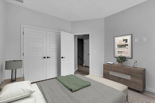 A bedroom with a bed, nightstand, and a painting on the wall.