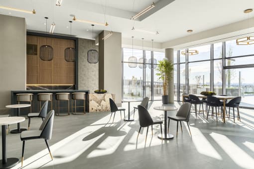 Interior photo of the club room showing multiple seating areas, dramatic lighting, large tile flooring and huge floor to ceiling windows.