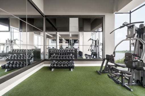 Interior photo of the gym at RVR showing a strength training machine and a complete rack of dumbells.