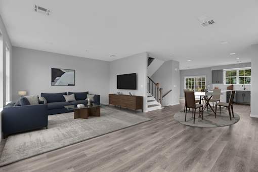 A modern living room with a dark blue sofa and wooden flooring.