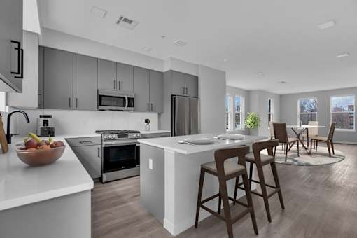 A modern kitchen with a white countertop and stainless steel appliances.