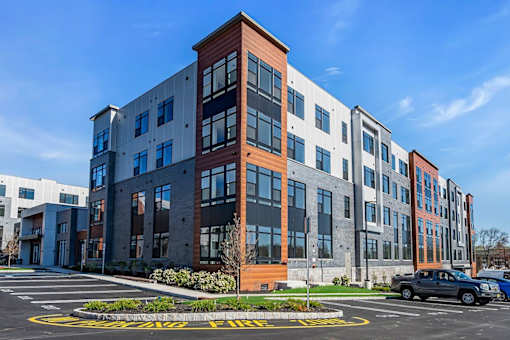 A modern multi-story building with a parking lot in front.