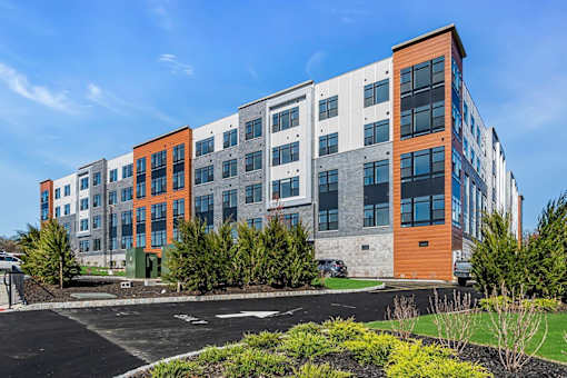 A modern multi-story building with a parking lot in front.