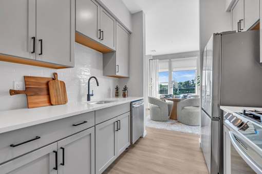A kitchen with grey cabinets and a wooden cutting board.