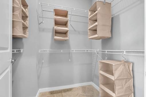 A room with a white wall and a shelf with bags hanging on it.