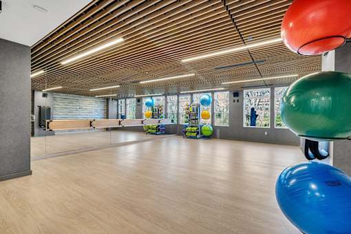 A gym with a wooden floor and a mirrored wall.