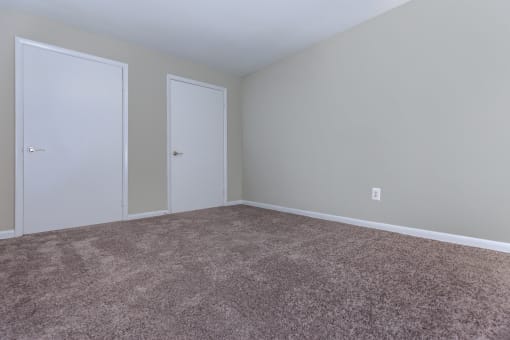 a bedroom with a carpeted floor and two doors at Highland Ridge, Maryland, 20743