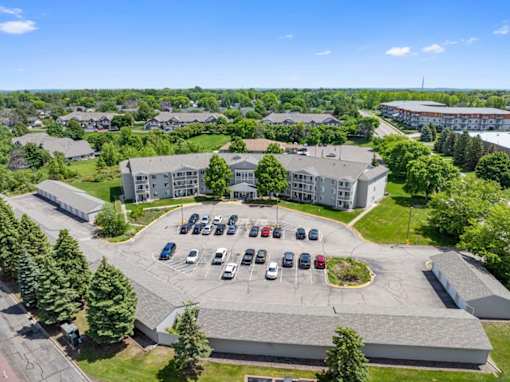 A parking lot in front of a building surrounded by trees.