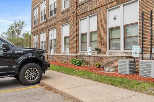 A black truck is parked on the side of a street in front of a brick building.