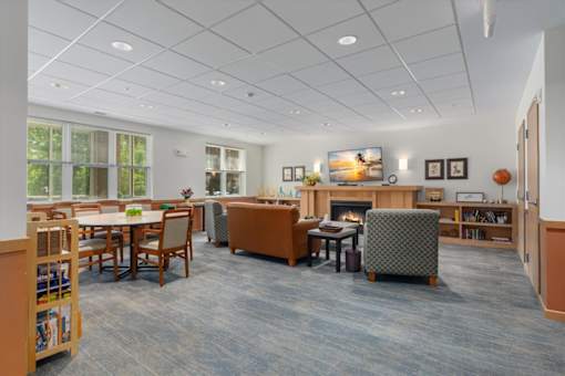 A spacious room with a fireplace, chairs, and a dining table.