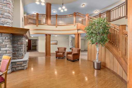 A living room with a stone fireplace and wooden floors.