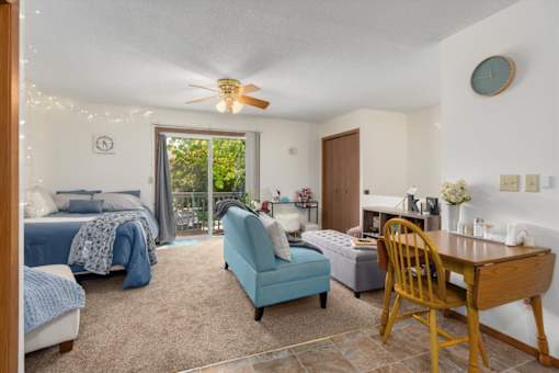 A bedroom with a bed, chair, and table.
