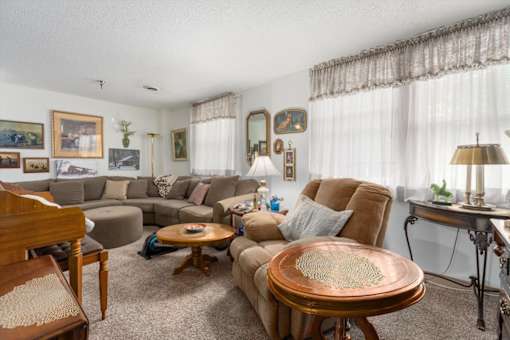 A living room with a brown couch, a wooden table, and a lamp.