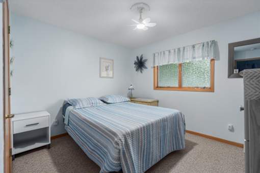 A bedroom with a bed, nightstand, and window.