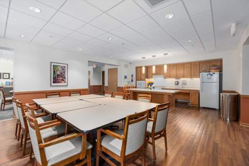 A kitchen with a table and chairs in the foreground and a refrigerator in the background.