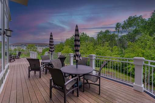A deck with a table and chairs overlooking a forest.