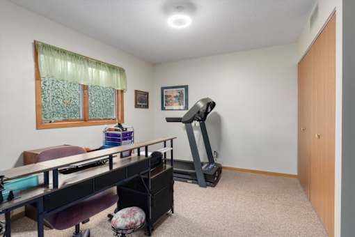 A room with a treadmill and a desk.