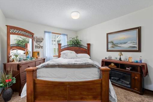 A bedroom with a bed, dresser, and a painting on the wall.