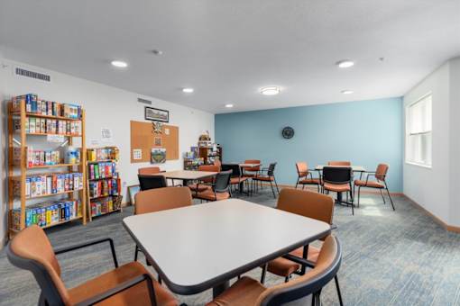 A room with a table, chairs, and a bookshelf.